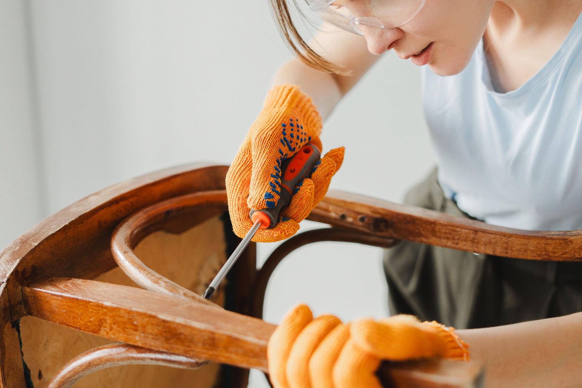 Woman restoring old wooden chair using screwdriver